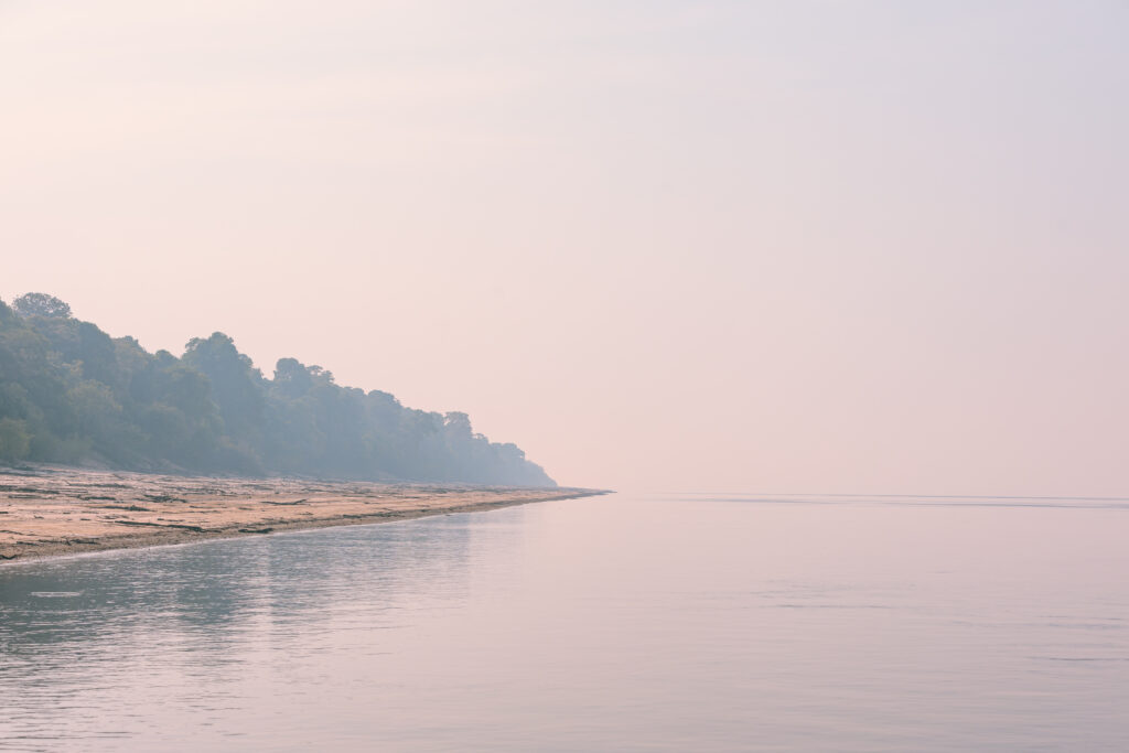 Rio Negro e ilha amazônica embaçados pela fumaça esbranquiçada das queimadas.